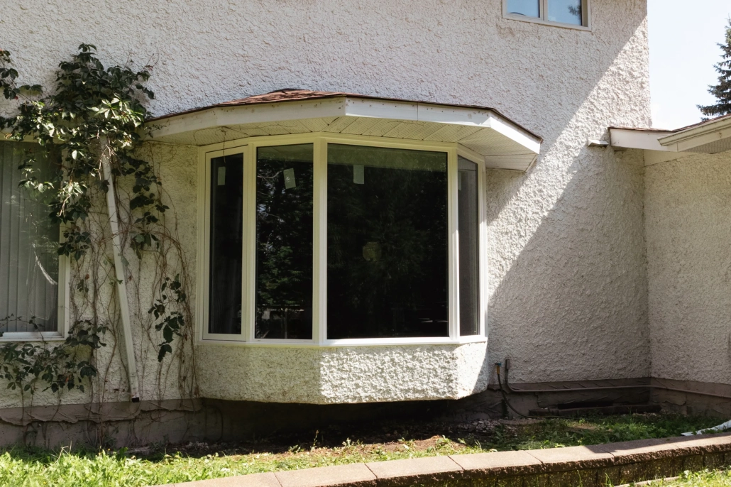 Exterior view of a custom bay window installed by Hi-Tech in Winnipeg's Charleswood neighbourhood. The window has one large pane of glass in the centre and two smaller angled panes on each side.