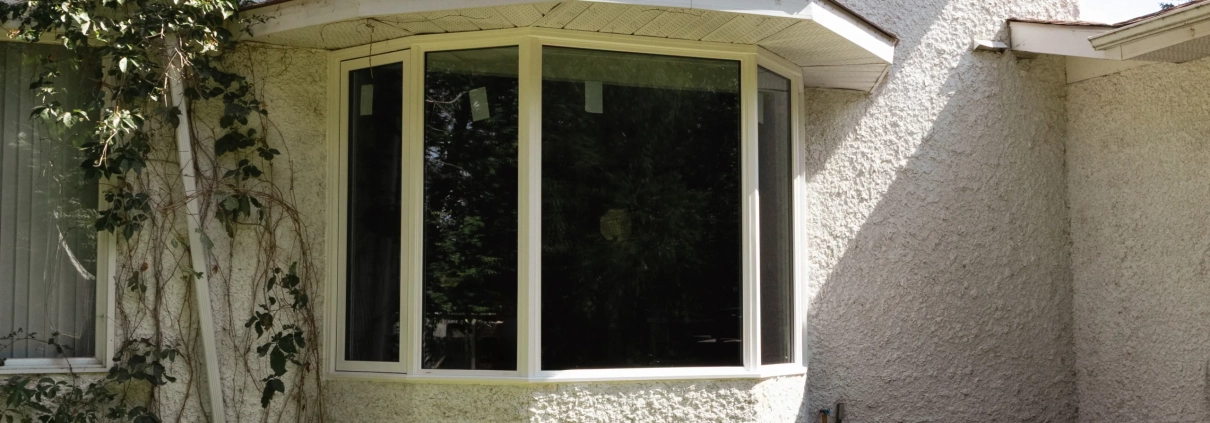 Exterior view of a custom bay window installed by Hi-Tech in Winnipeg's Charleswood neighbourhood. The window has one large pane of glass in the centre and two smaller angled panes on each side.