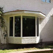 Exterior view of a custom bay window installed by Hi-Tech in Winnipeg's Charleswood neighbourhood. The window has one large pane of glass in the centre and two smaller angled panes on each side.