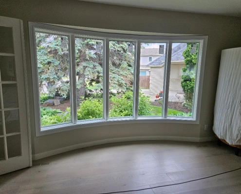 Interior view of a custom bow window installed by Hi-Tech. The window has a solid frame and five panes of glass, angled in a gentle curve.