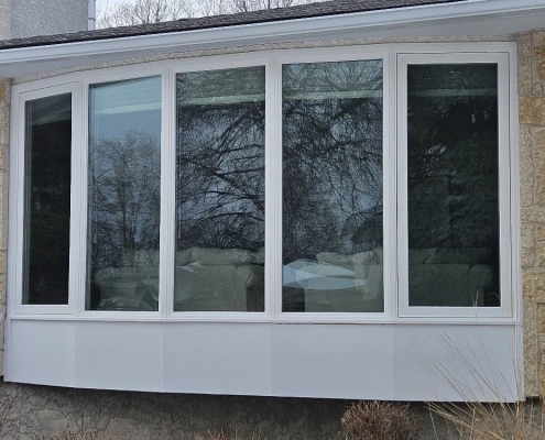 Exterior view of a new bow window installed by Hi-Tech. It has five gently-angled panes of glass and a white window frame.