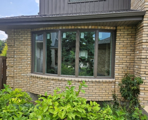 Exterior view of an energy-efficient bow window installed by Hi-Tech. The window has a solid frame and five panes of glass, angled in a gentle curve.